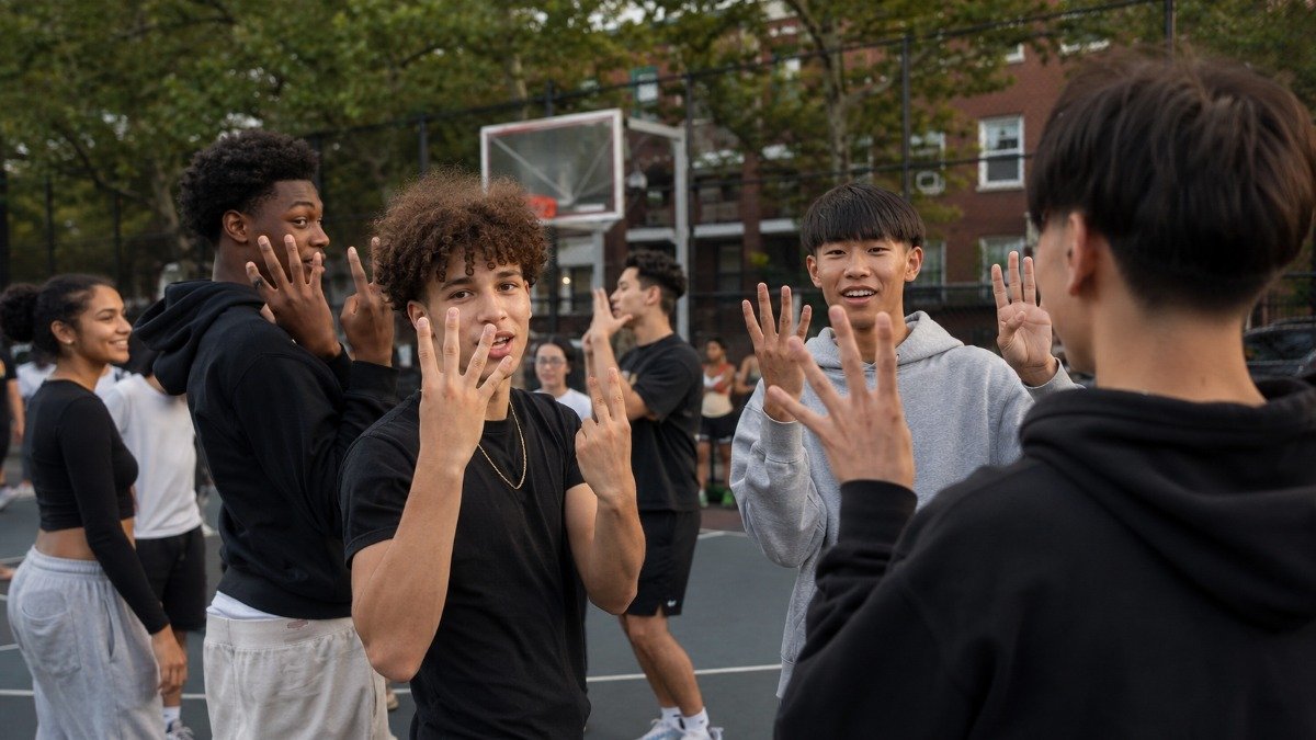 jovens fazendo gesto de six-seven em quadra de basquete